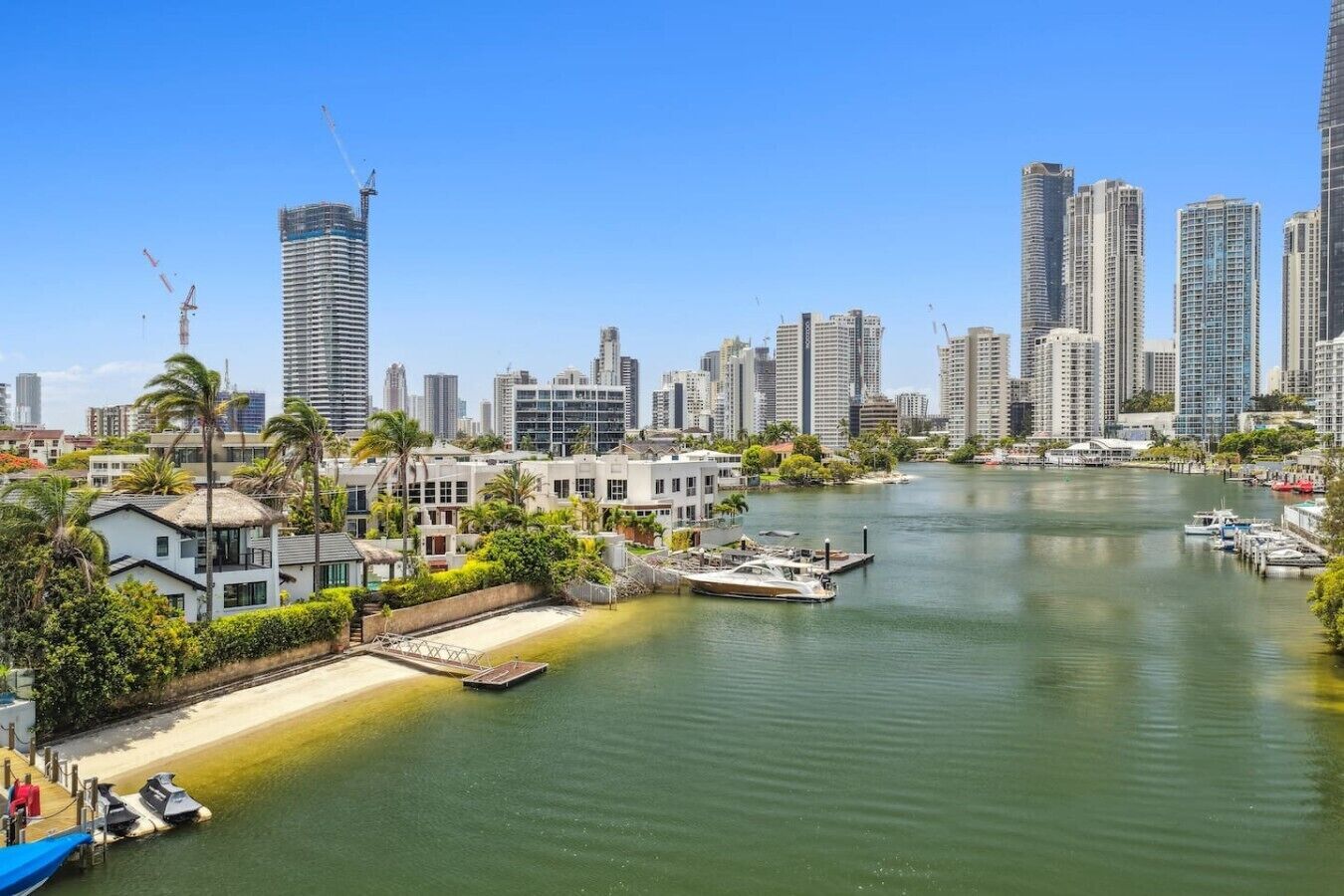 A waterfront cityscape with high-rise buildings, a marina, and a dock with boats.