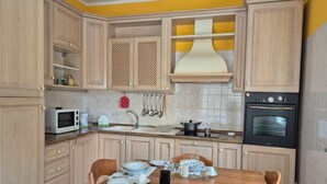 Uma cozinha com armários de madeira, micro-ondas, fogão e uma mesa de jantar posta com pratos e copos.