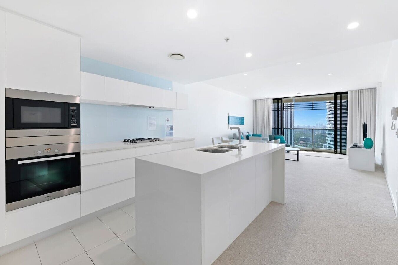 A modern kitchen with built-in appliances, a central island, and a view of the city.