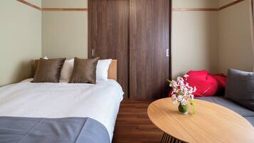 Una habitación de hotel con cama, sofá, mesa de madera y armario.