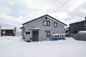 A residential building with a gabled roof, a front door, and a small porch area.