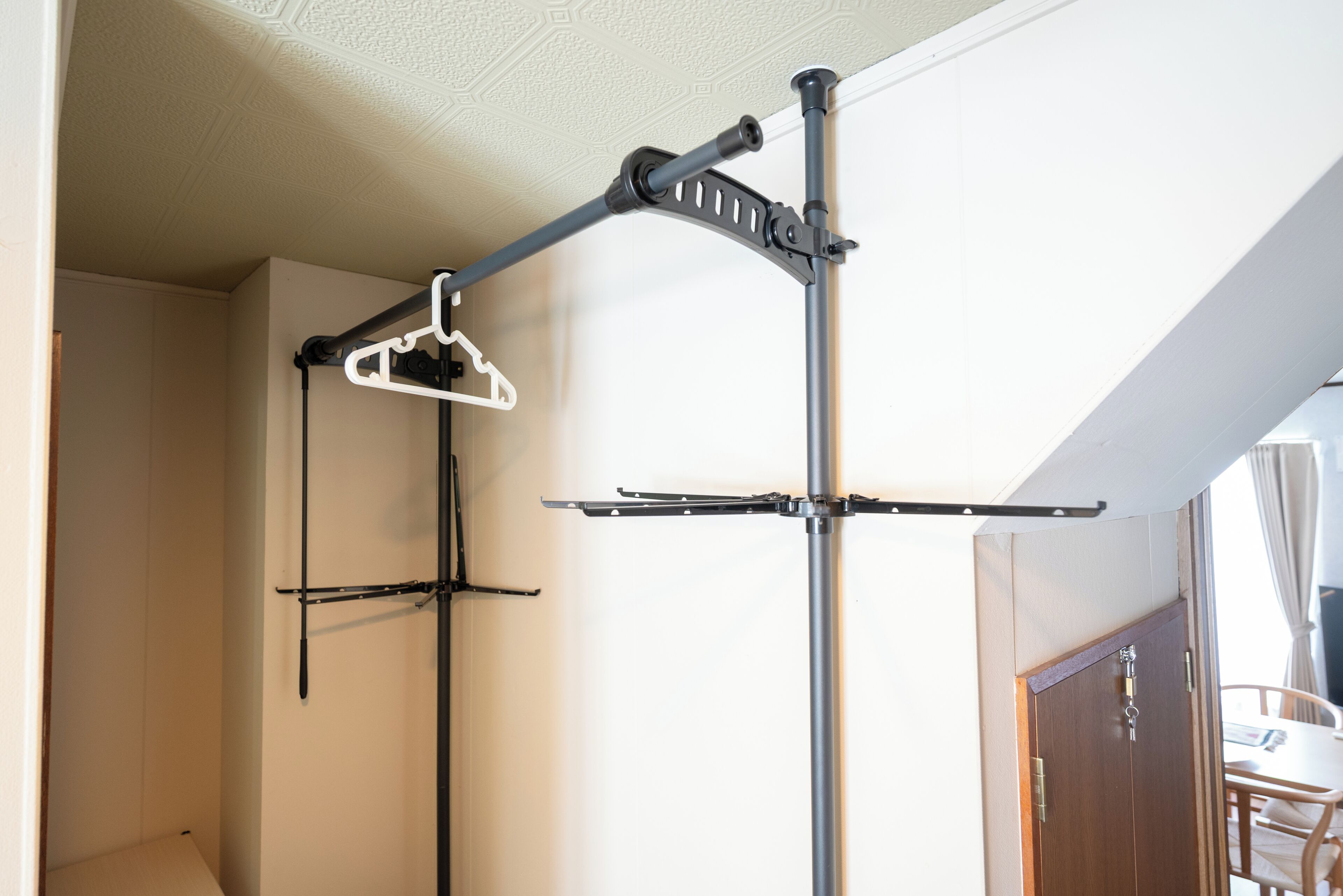 A room with a ceiling-mounted drying rack, a door, and a table with chairs.