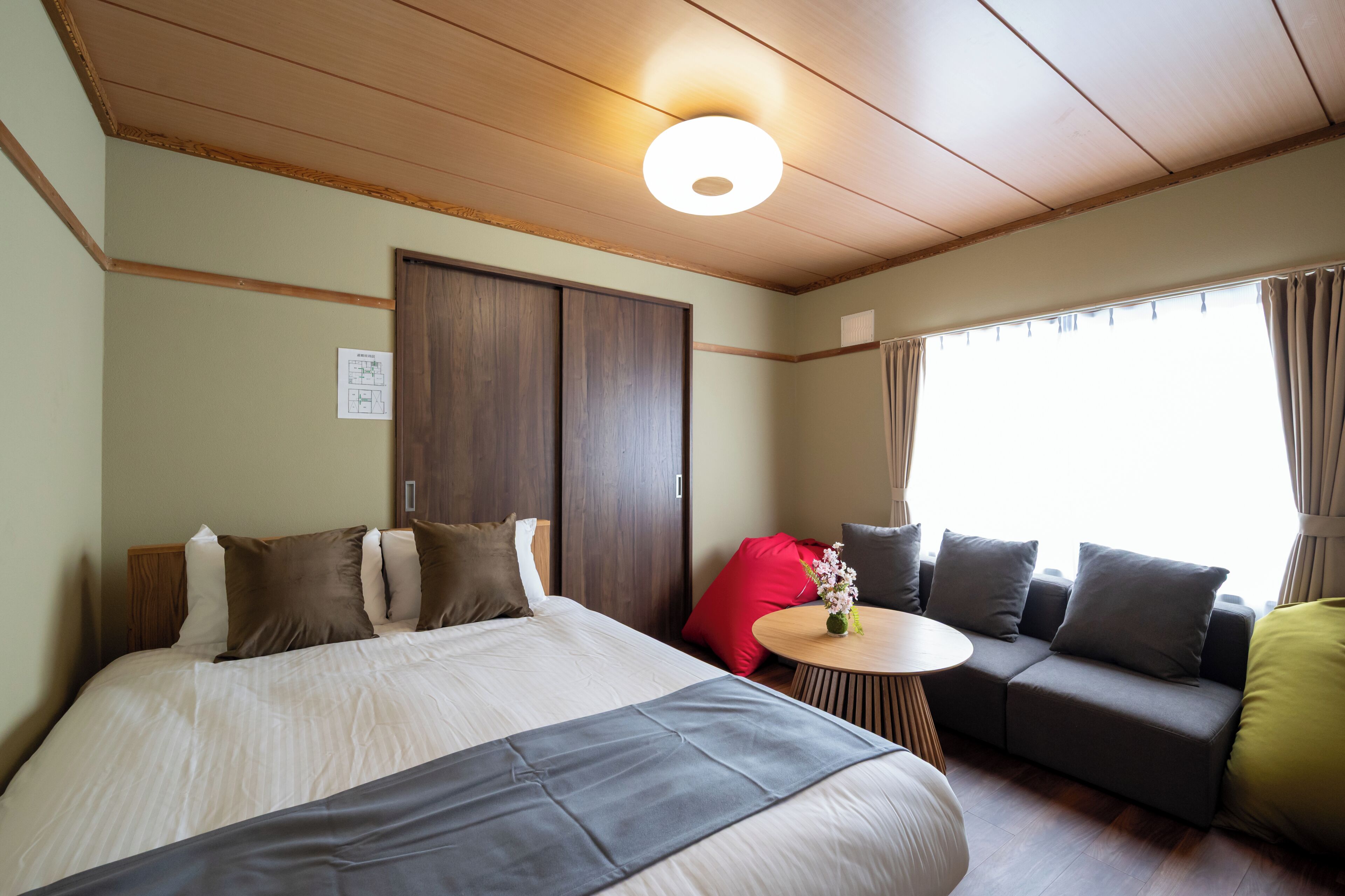 Une chambre d’hôtel avec un lit, un canapé, une petite table et une fenêtre avec des rideaux.