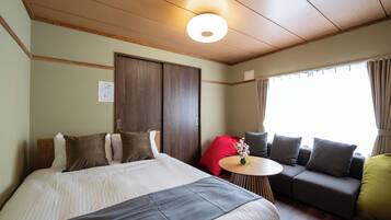 Une chambre d’hôtel avec un lit, un canapé, une petite table et une fenêtre avec des rideaux.