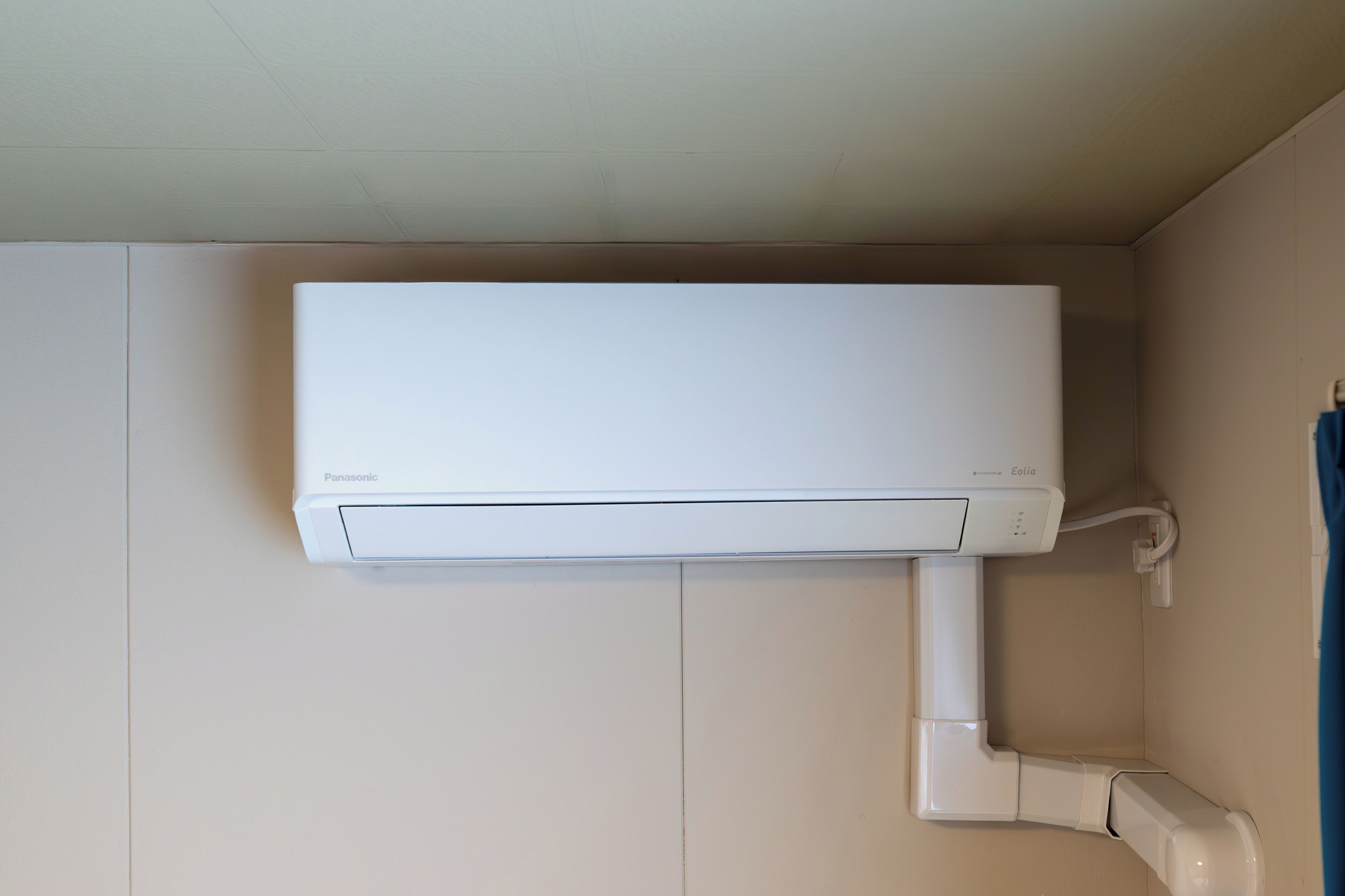 Un equipo de aire acondicionado blanco montado en una pared, con una tubería visible.