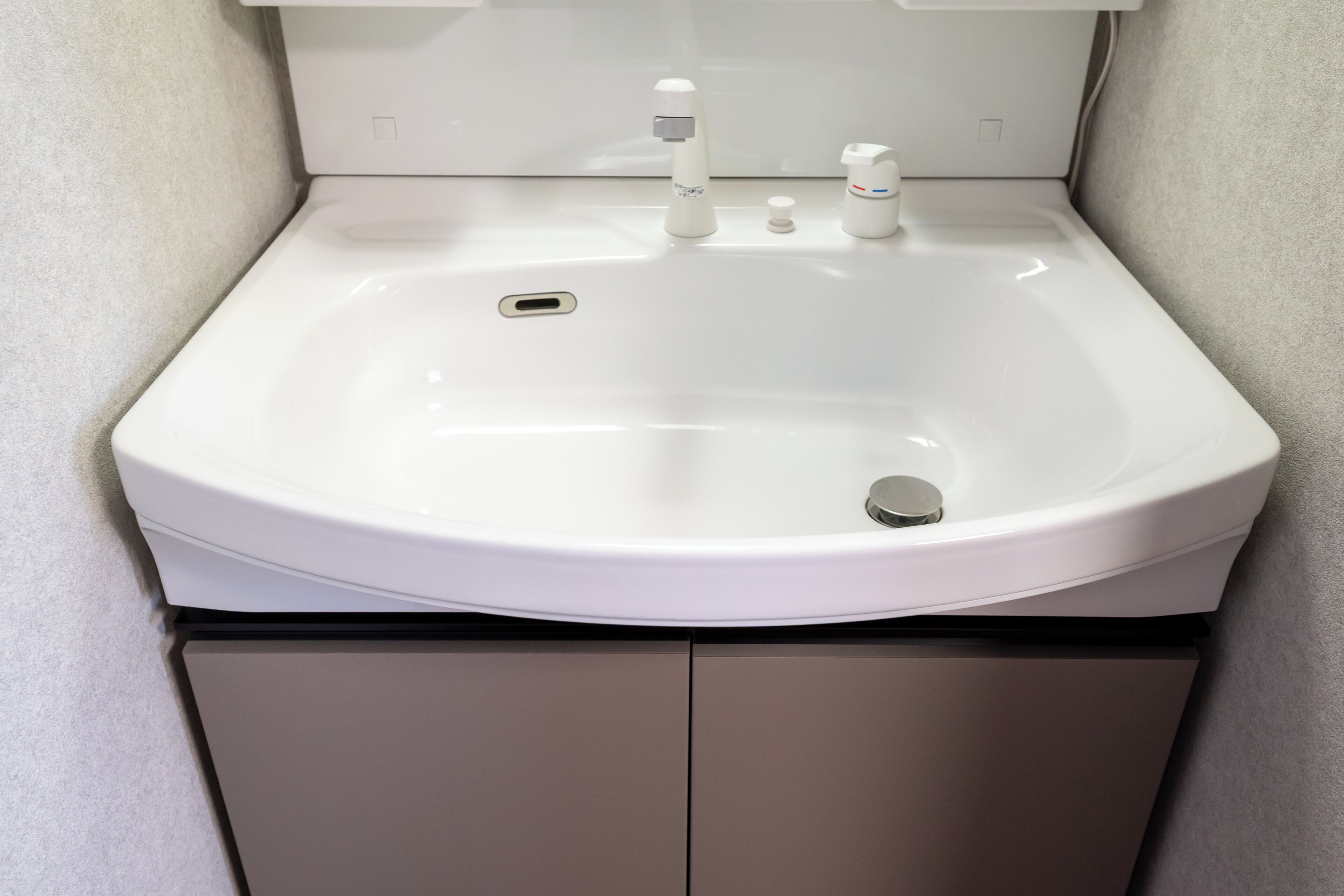 A white bathroom sink with a mirror above it, a faucet, and a soap dispenser.