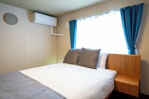 A hotel room with a bed, a nightstand, a clock, and a window with curtains.