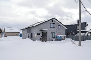 A residential building with a sloped roof, a front door, and a small porch area. - Nakafurano Nature Retreat (Sorachi-gun,Nakafurano-cho)