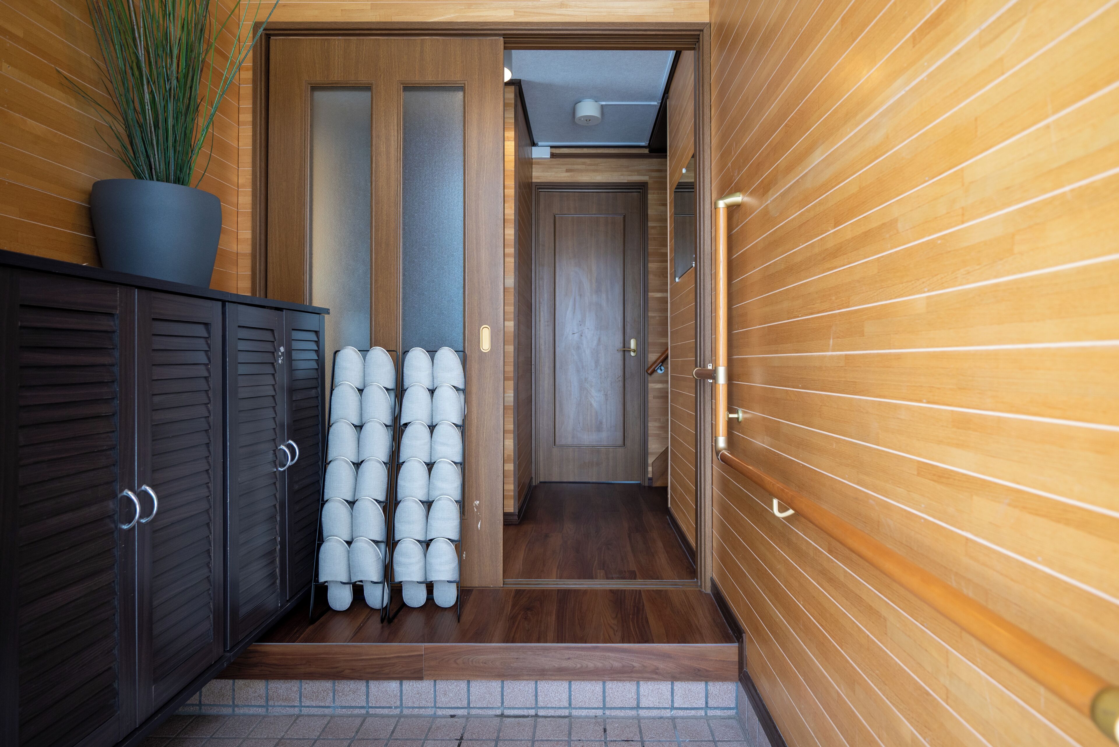 Ein Korridor mit Holzwänden, einem Blumentopf, einem Schrank und einer Reihe weißer Helme.
