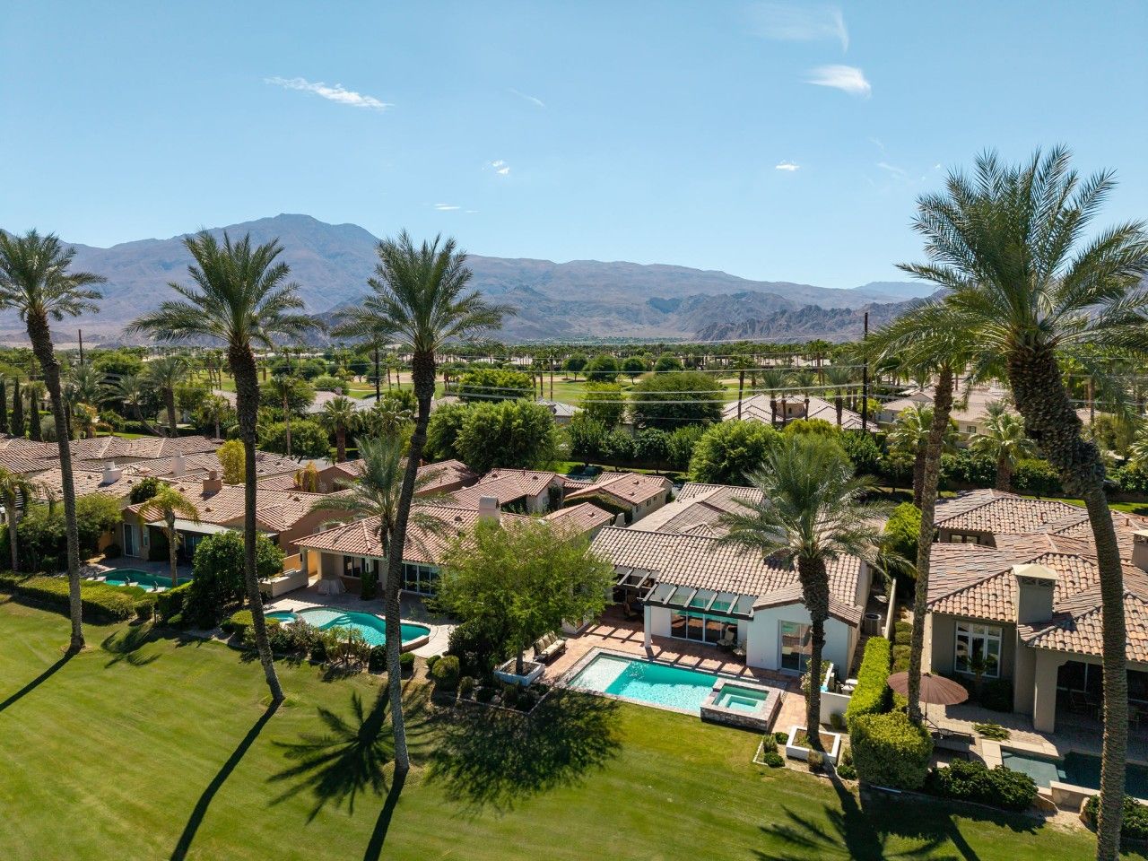 A residential area with multiple houses, a swimming pool, and palm trees.