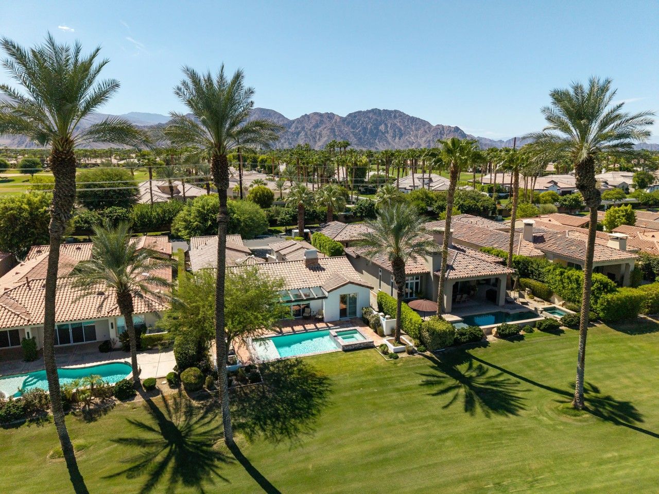 A residential area with multiple houses, a swimming pool, and palm trees.