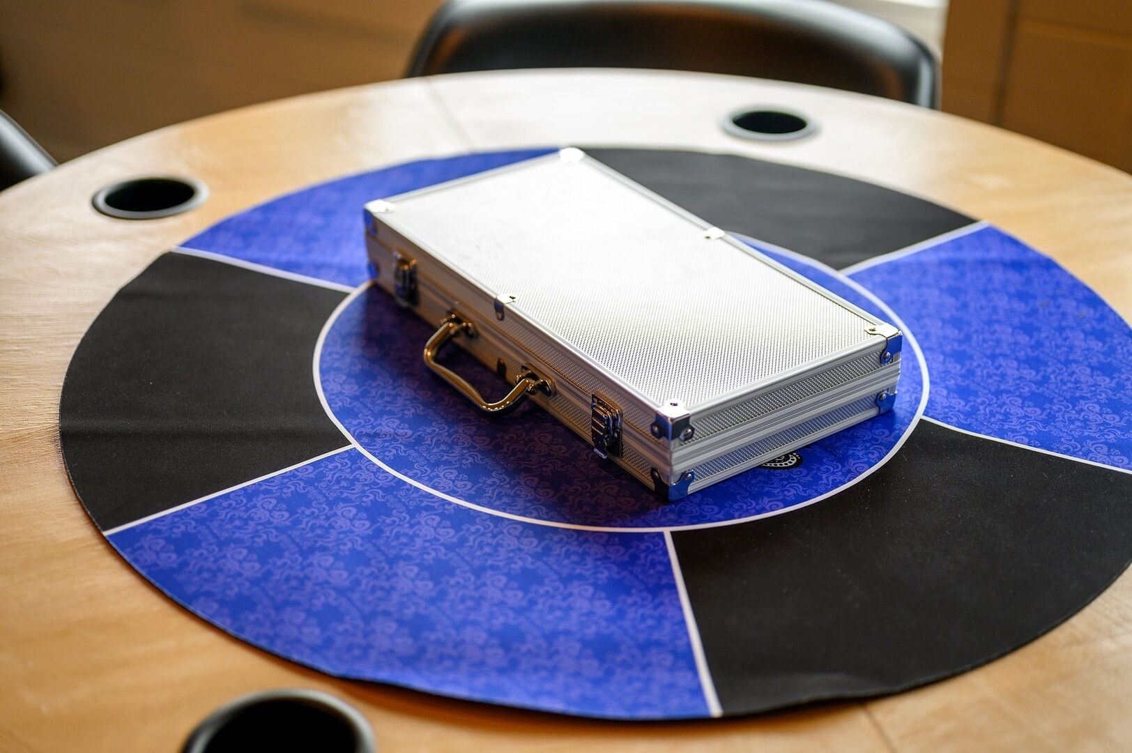 A projector on a table with a circular blue and black mat.