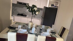 A dining area with a glass table, four cushioned chairs, a vase with flowers, and a kitchen in the background. - Fabulous 3-bedroom house in enjoyable Ensenada for your getaway (Ensenada)
