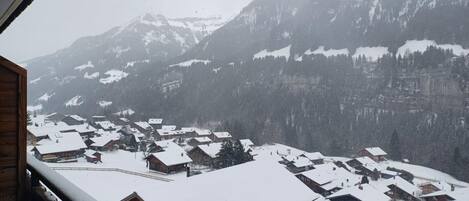 A snowy mountain village with traditional wooden houses and a view of snow-covered peaks.