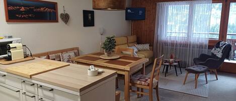 Eine moderne Küche mit Essbereich, einer Couch und einem Fernseher.