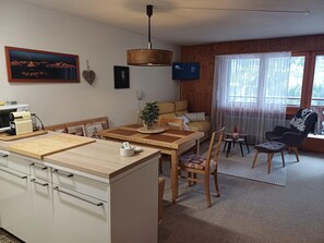 A modern kitchen with a dining area, a sofa, and a TV. - Le Cocon, (Champery), by Interhome (Champery)