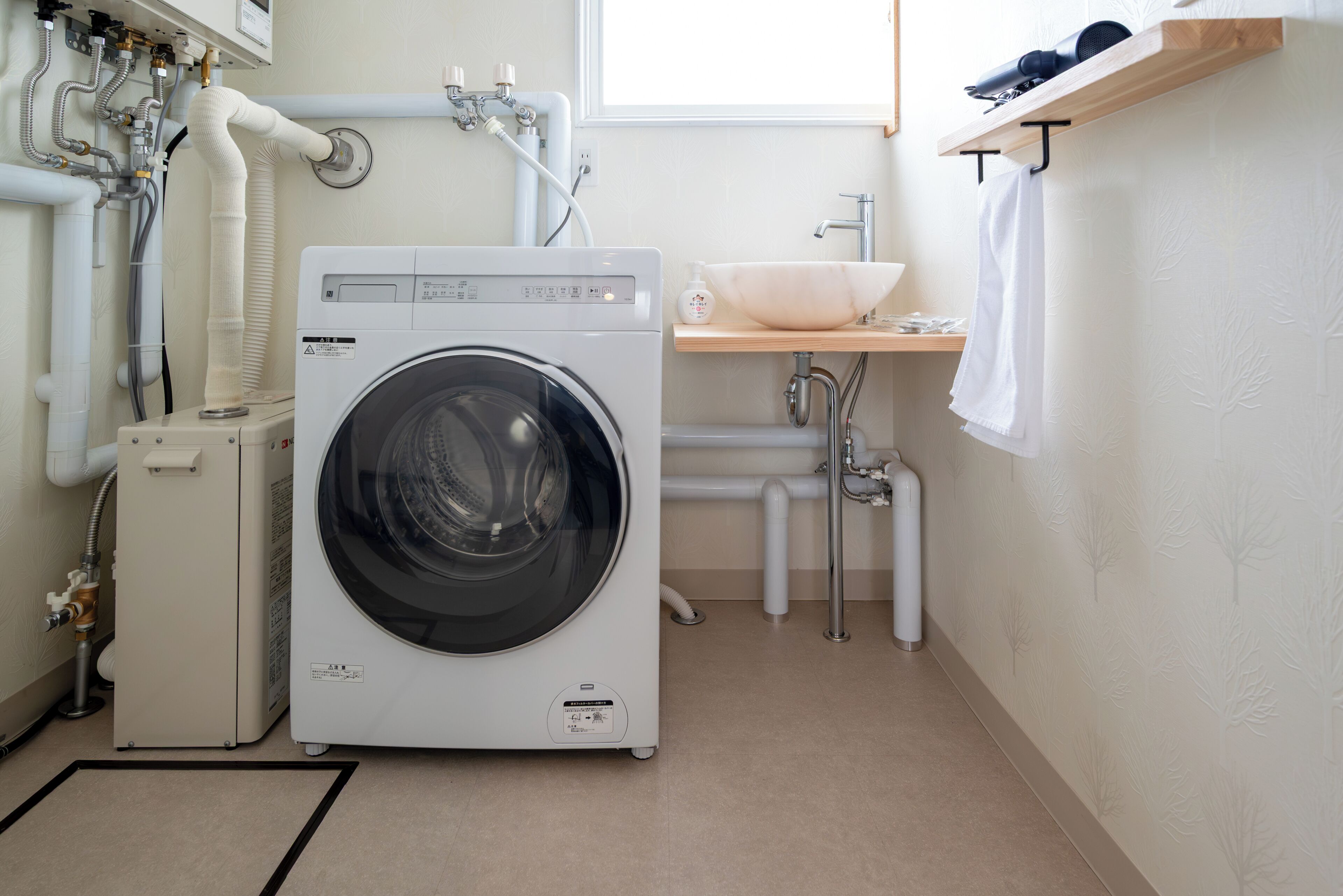 A compact laundry room with a front-loading washing machine, a sink, and a towel rack.