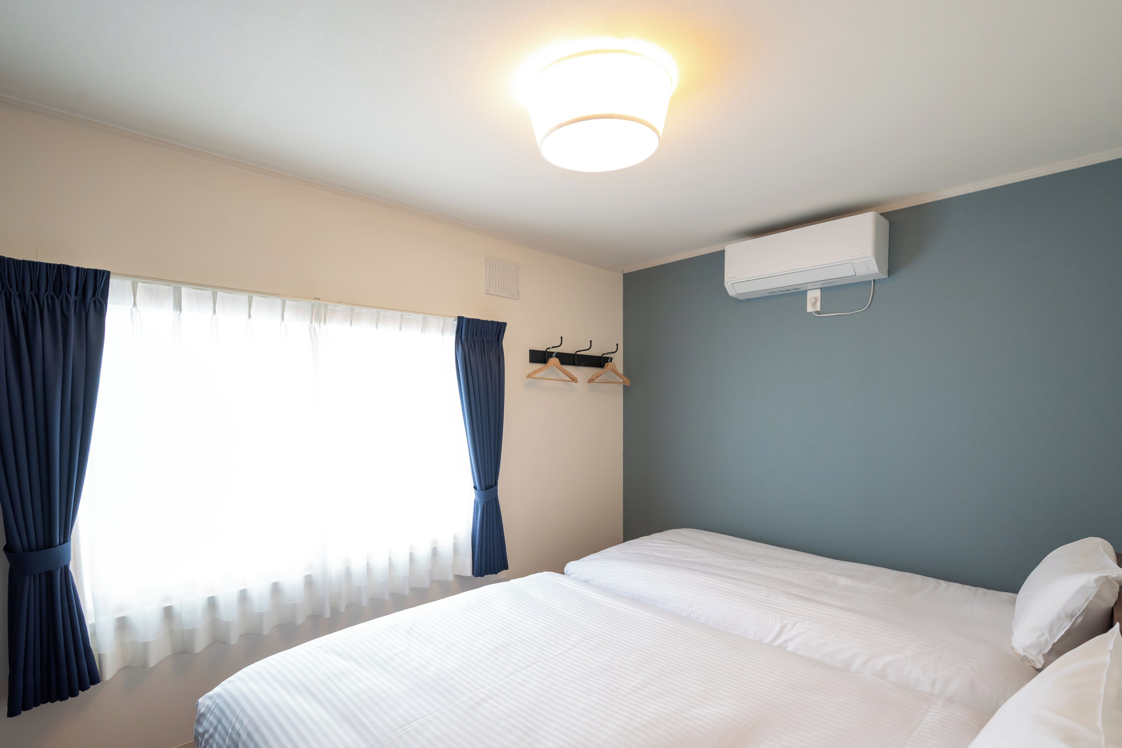 Quarto de hotel com cama, janela com cortinas, ar condicionado e luminária.