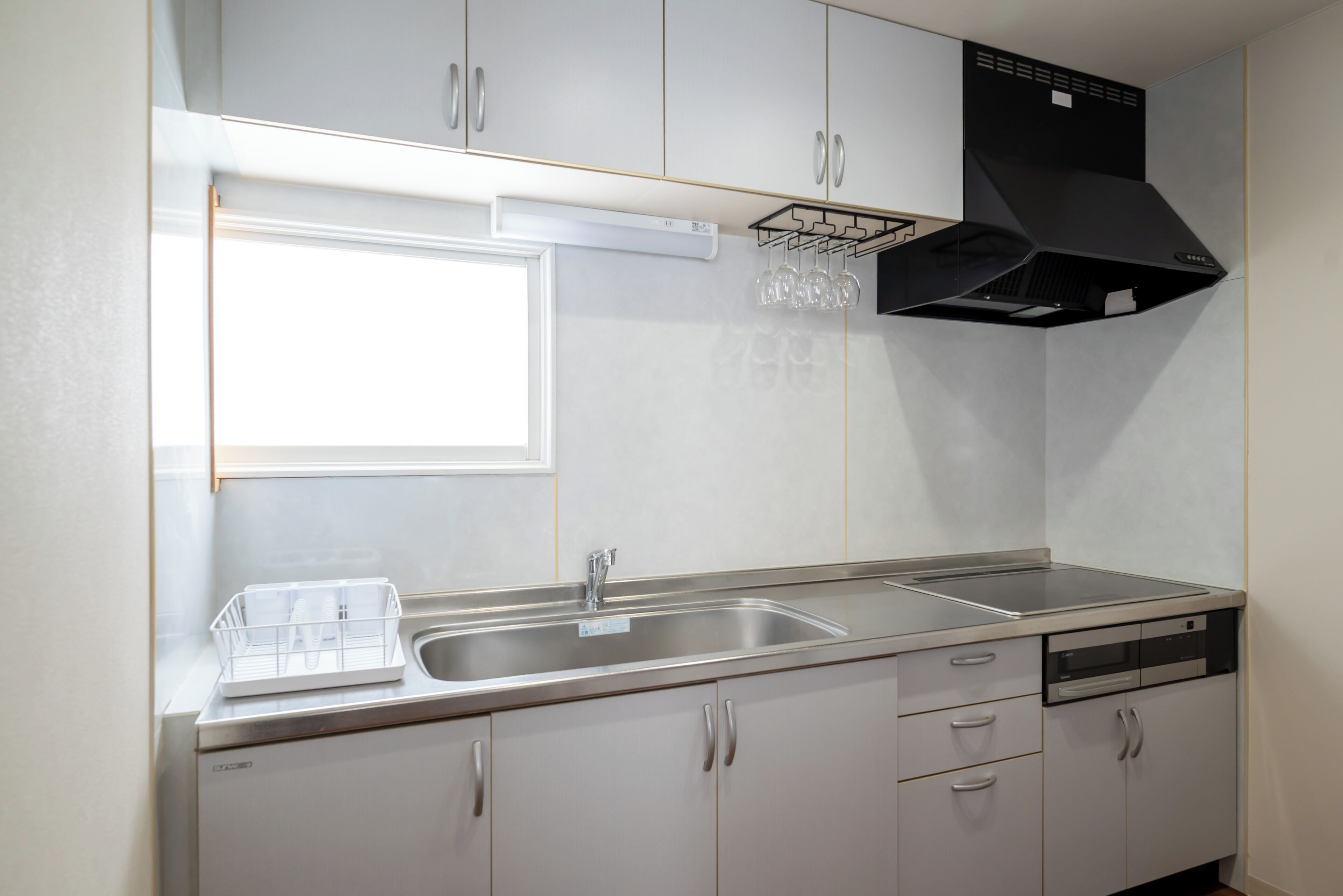 A modern kitchen with a stainless steel sink, a dishwasher, and a black range hood.