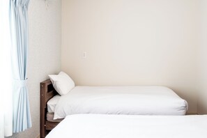 A single bed with white bedding, a wooden headboard, and a light blue curtain. - Villa Shigin (Sorachi-gun,Nakafurano-cho)