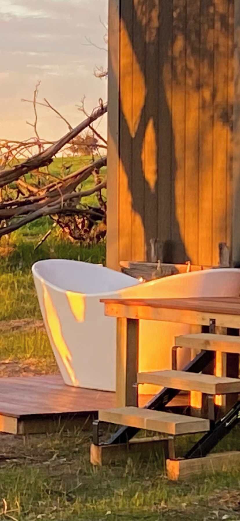Entorno rústico al aire libre con una mesa de madera y una bañera blanca.