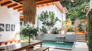 Eine moderne Außenpatio mit Pool, Holzbänken und verschiedenen Kübelpflanzen.
