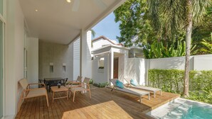 A wooden deck with outdoor furniture, a pool, and a white building with a covered patio area. - Private Pool Villa Oxygen Bangtao 3BR (Tambon Choeng Thale)