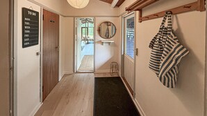 Un couloir avec une pancarte indiquant « choses à faire », une pancarte indiquant les toilettes, un miroir, une serviette suspendue et une porte donnant sur une pièce.