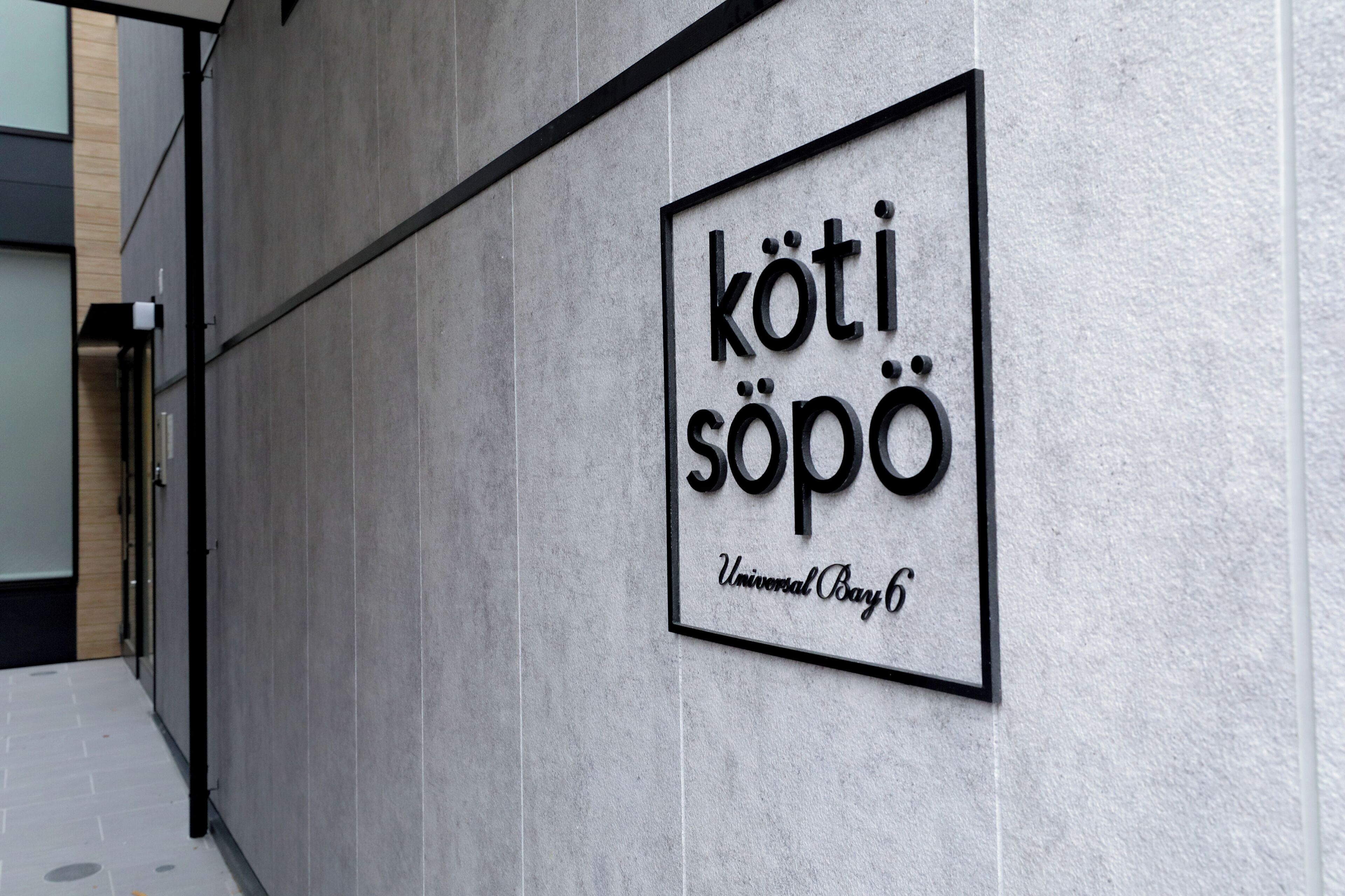 Un letrero con el texto 'kötisöpo' y 'Universal Bay 6' en una pared.