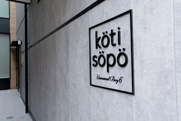 A sign with the text 'kötisöpo' and 'Universal Bay 6' on a wall. - Koti Sopo Universal Bay 6 by Liaison (Osaka)