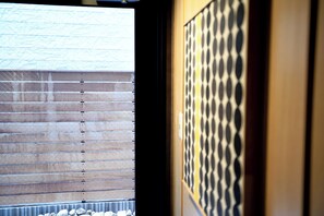 Ein Zimmer mit Fenster, horizontalen Jalousien, einer Wand mit Muster und einer Holztür.