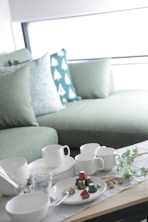 A dining area with a table set with white dishes, cups, and a plate with food items. - Koti Sopo Universal Bay 6 by Liaison (Osaka)