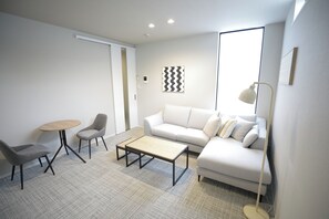 A modern living room with a sofa, two armchairs, a coffee table, and a floor lamp.