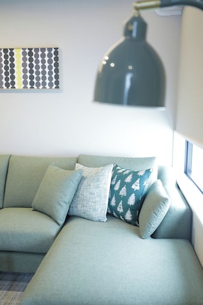 Ein modernes Wohnzimmer mit einer Eckcouch, einer Wanddekoration und einer Stehlampe.