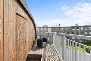 A wooden balcony with outdoor seating, overlooking a residential area with multi-story buildings. - City-Center Gem with Prime Reykjavík Access (Reykjavík)