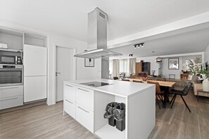 A modern kitchen with a central island, built-in oven, and a stainless steel range hood. - City-Center Gem with Prime Reykjavík Access (Reykjavík)