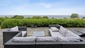 Een terras met rieten meubilair en uitzicht op zee.