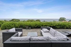 Ein Außenbereich mit Korbmöbeln und Blick aufs Meer.