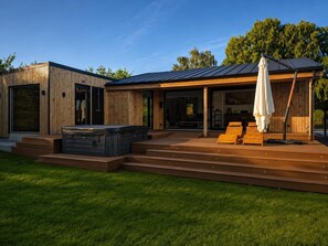 A modern house with a hot tub, outdoor seating, and a covered patio. - Newly renovated cottage with sauna (Melby)