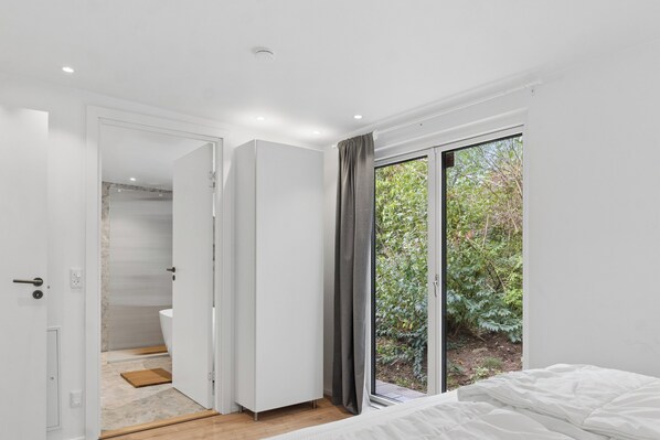 Un dormitorio moderno con un ventanal grande, una cama y un vestidor.
