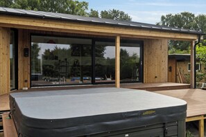 Un edificio moderno con fachada de madera, amplios puertas correderas de vidrio y un área exterior cubierta.