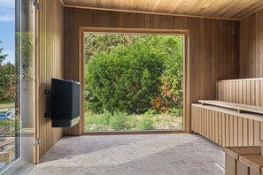 Ein modernes Zimmer mit einer großen Schiebeglasdoor, einem an der Wand montierten Flachbildfernseher und einer Holzbank.