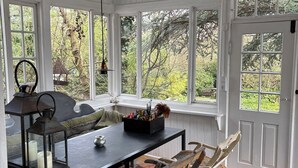 Una habitación con un ventanal grande, una mesa, un banco y un farol.