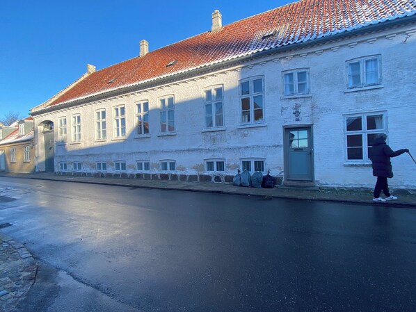 Un bâtiment historique avec un toit recouvert de tuiles rouges, des murs blancs et une personne qui pousse un chariot.