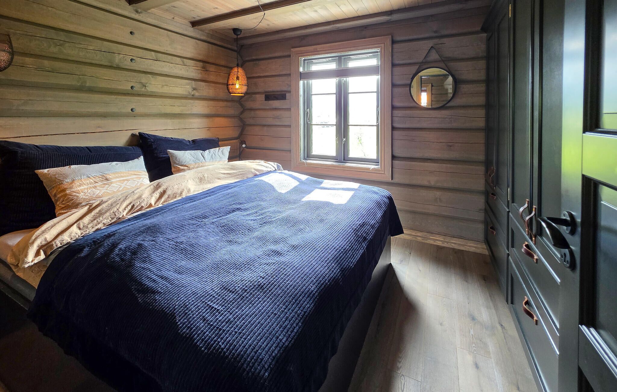 A wooden cabin-style room with a bed, a window, and a dresser.