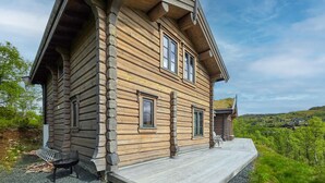 En hytte med veranda, bænk og udsigt over det omkringliggende landskab.