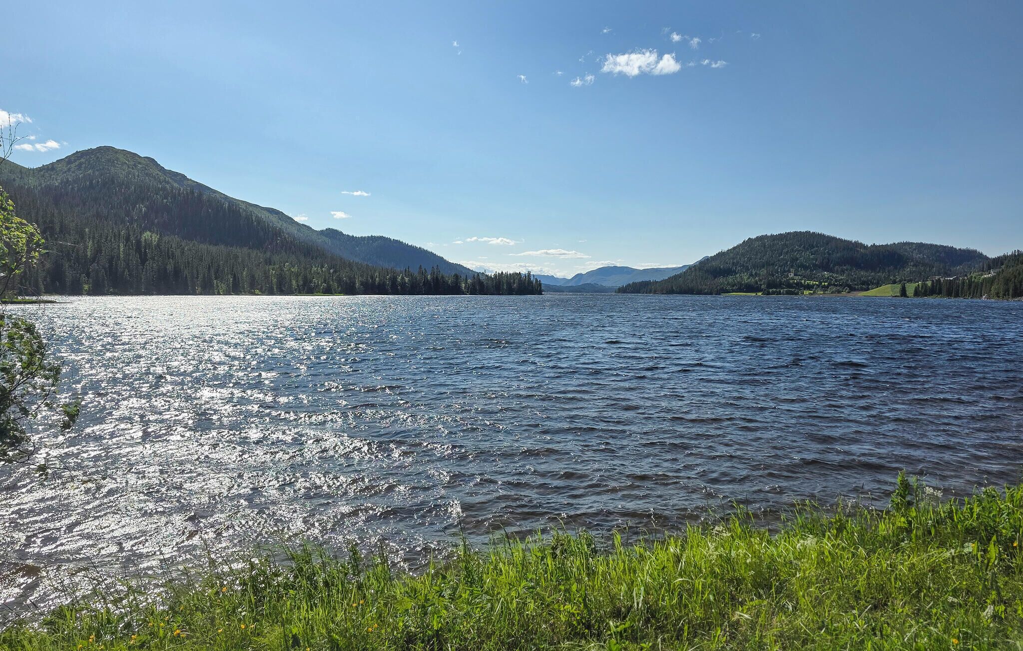 A calm lake with forested hills in the background.