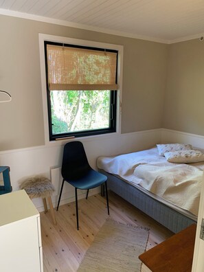 Un dormitorio con cama, una silla, un escritorio y una ventana con persianas.