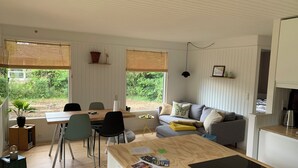 Een moderne keuken met een eethoek, een bank en uitzicht op groen.
