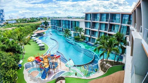A hotel with a swimming pool, a children's play area, and a view of the surrounding landscape.